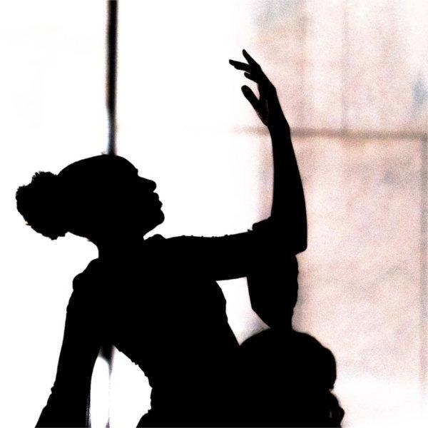 A dancer is silhouetted with the hand in the air.