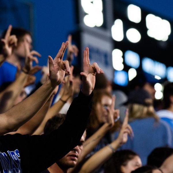 GVSU Students at a football game holding their hands up in the Laker L.