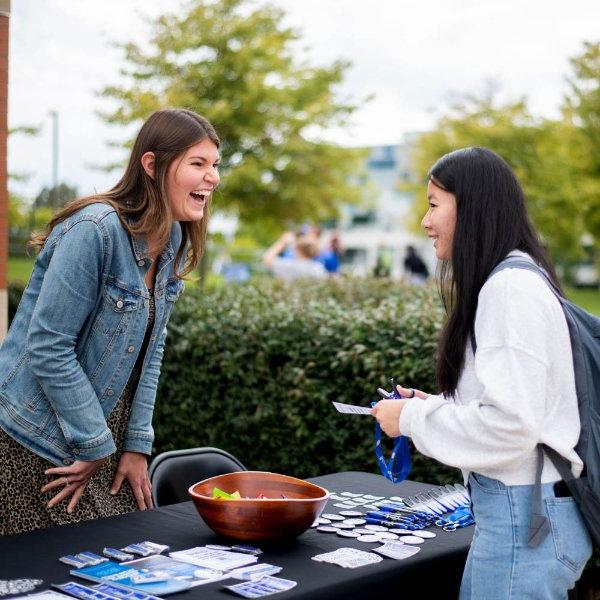 A woman speaks to a student over a table covered in small hand-outs.